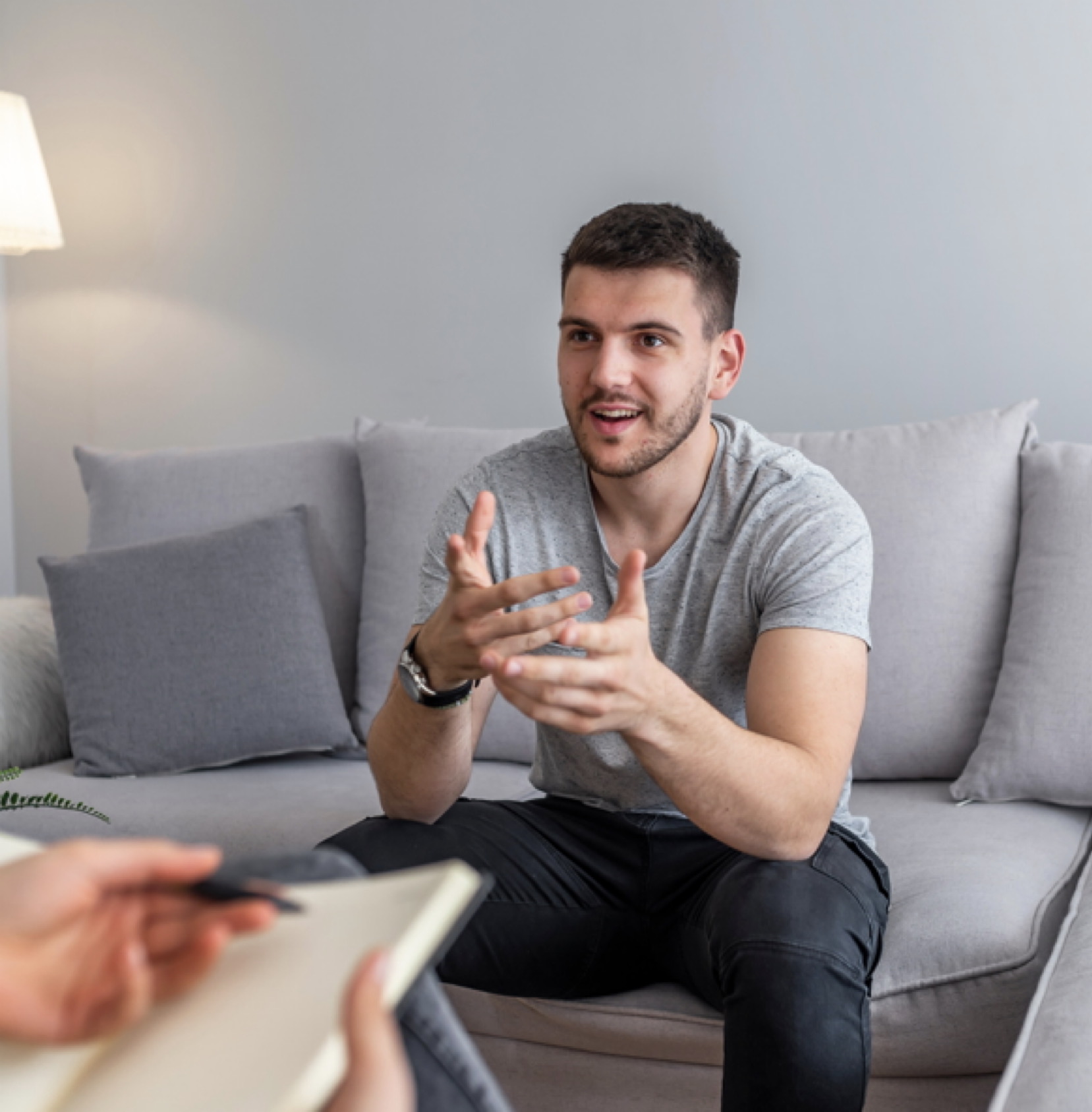 Psychologist talking with happy man in the office. Image of young man during psychological therapy. Female psychologist consulting man during psychological therapy session
